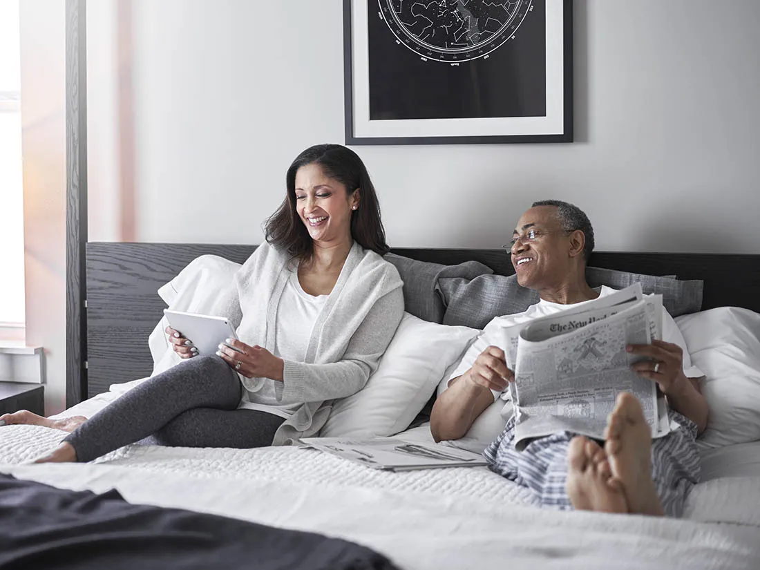 Two people laughing and laying in bed