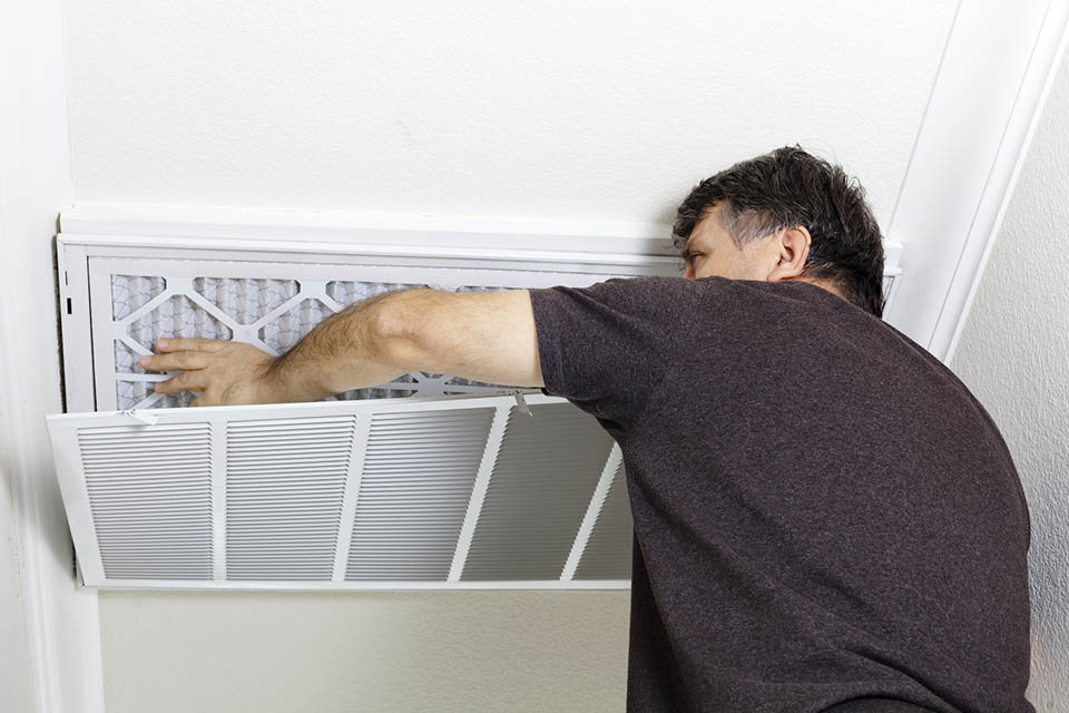 Man replacing a filter on a home air conditioning system.