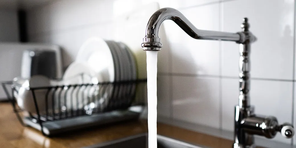 Water flowing out of a kitchen tap into the sink.