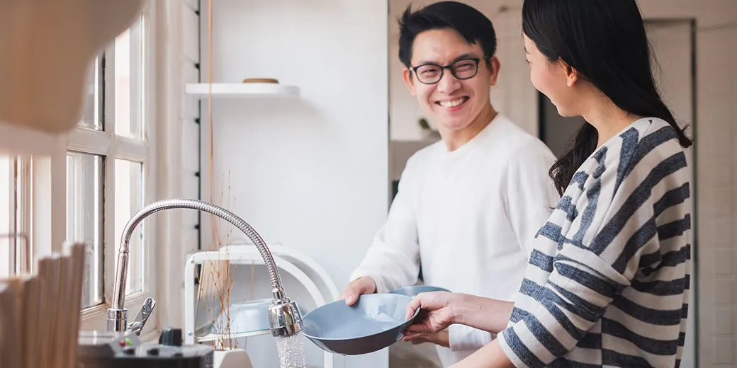 A family washing dishes together at the kitchen sink