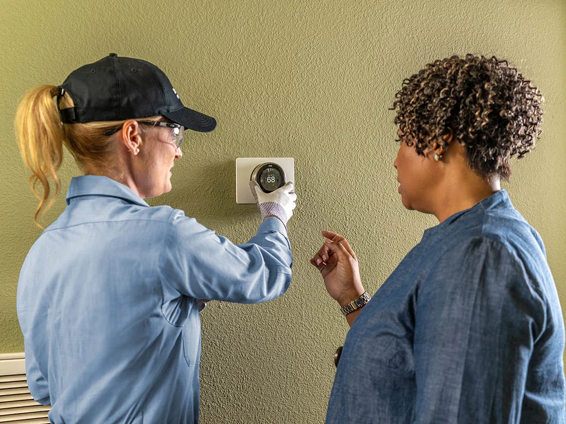 Technician and homeowner looking at smart thermostat