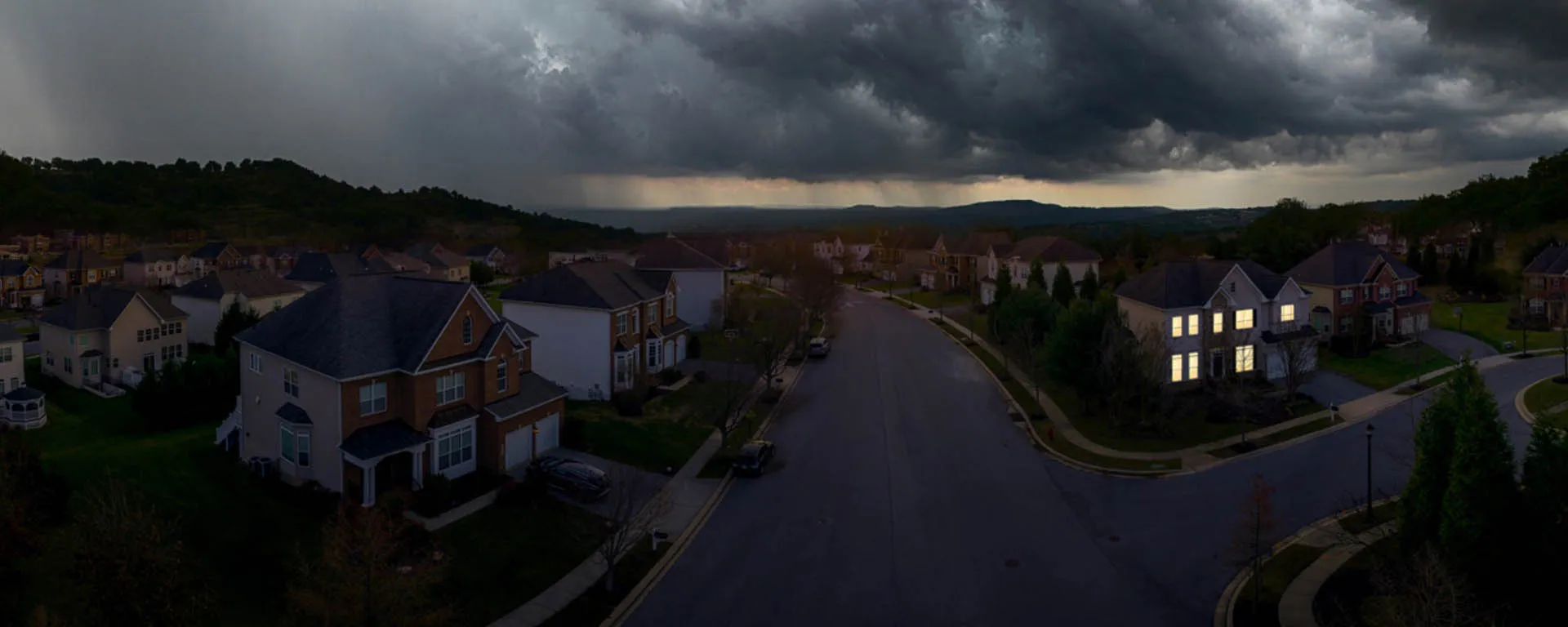 Dark neighborhood with one house exhibiting lights on by generator